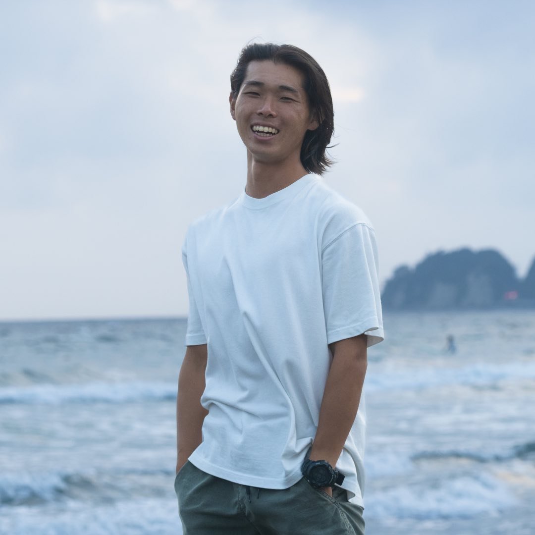 海辺で笑顔を見せる杉井太一さん